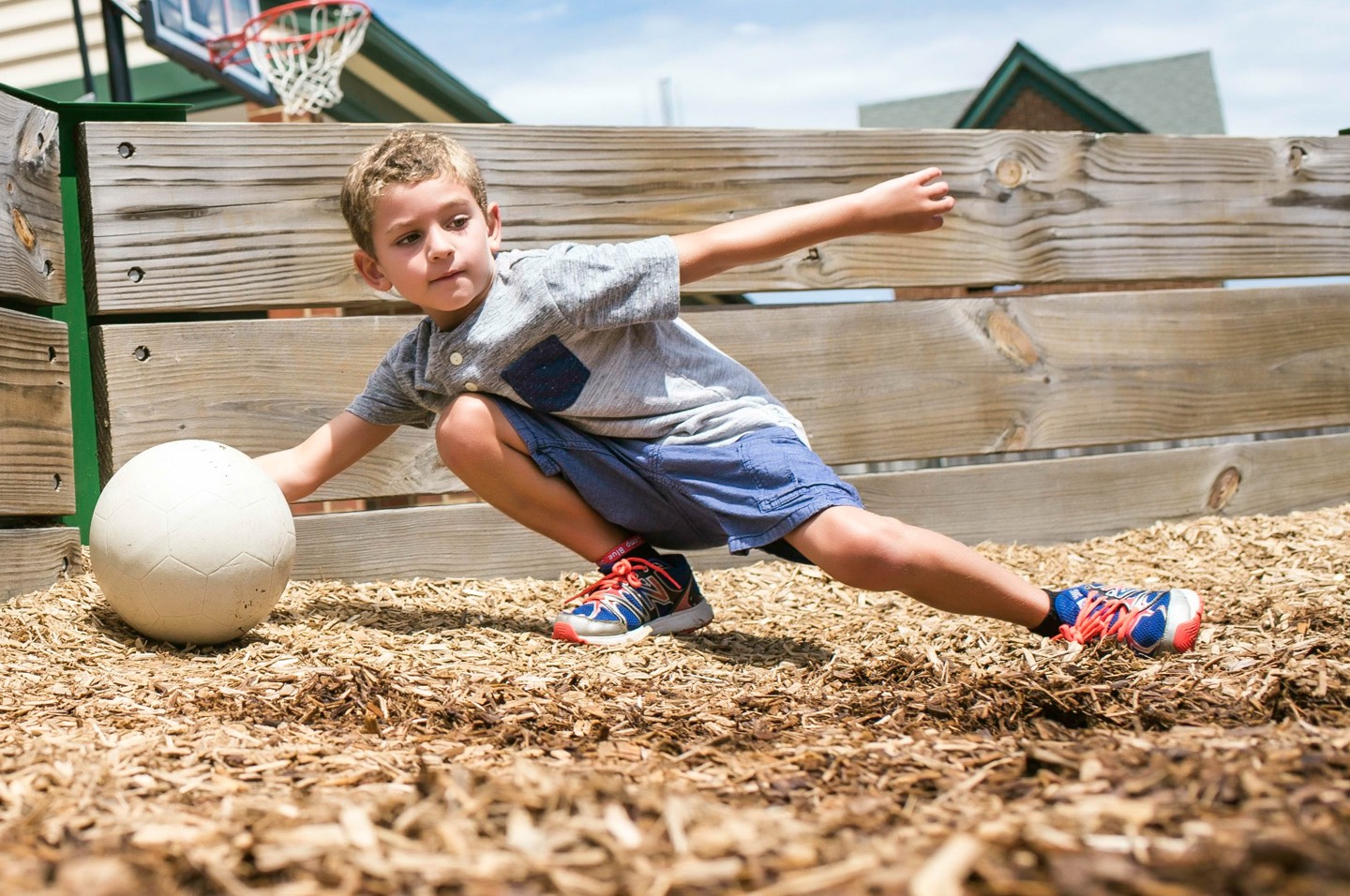 Boy grabbing ball in a mulched play-area